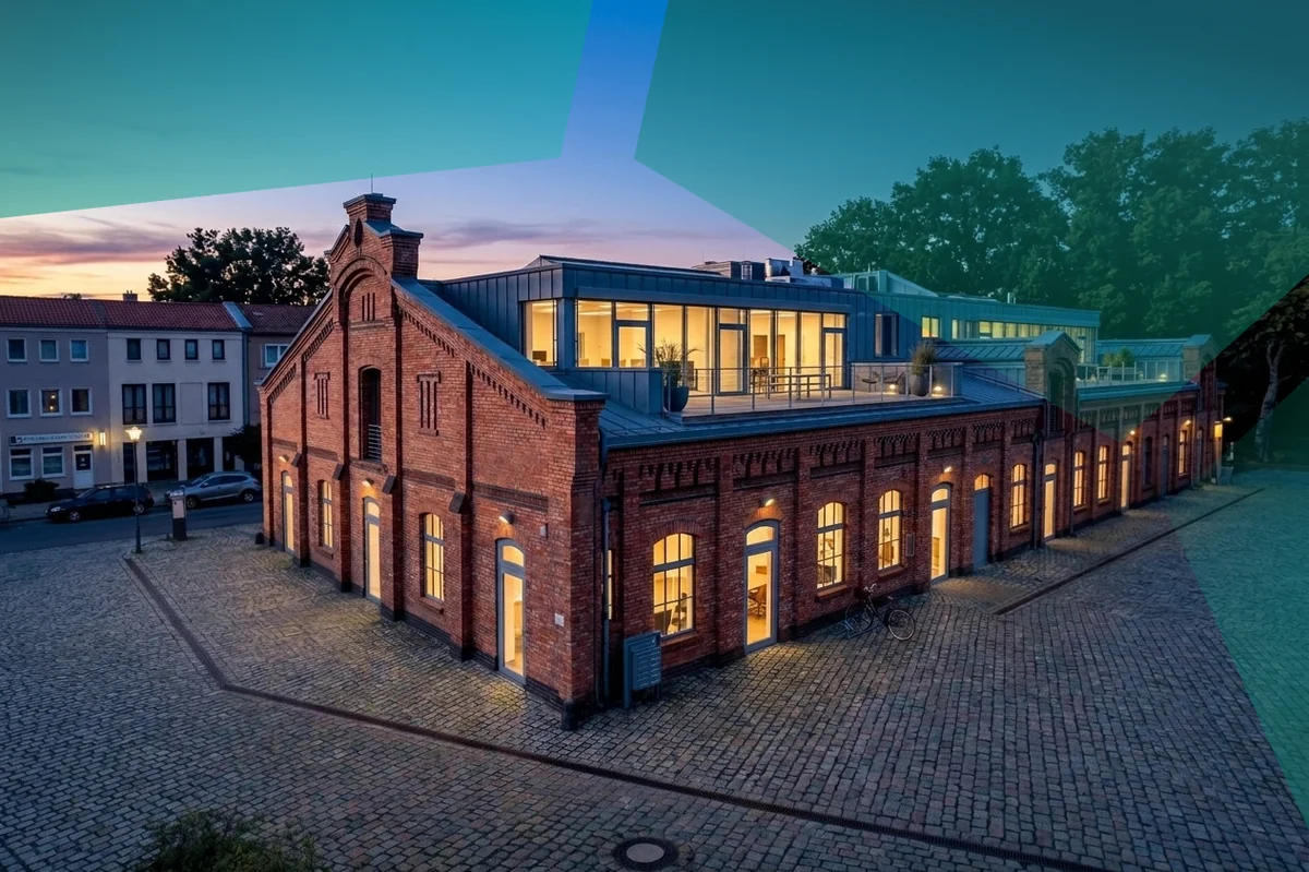 Abendaufnahme des Beyond-Horizon-Büros in Berlin, ein sanierter Backsteinbau mit verglastem Dachgeschoss